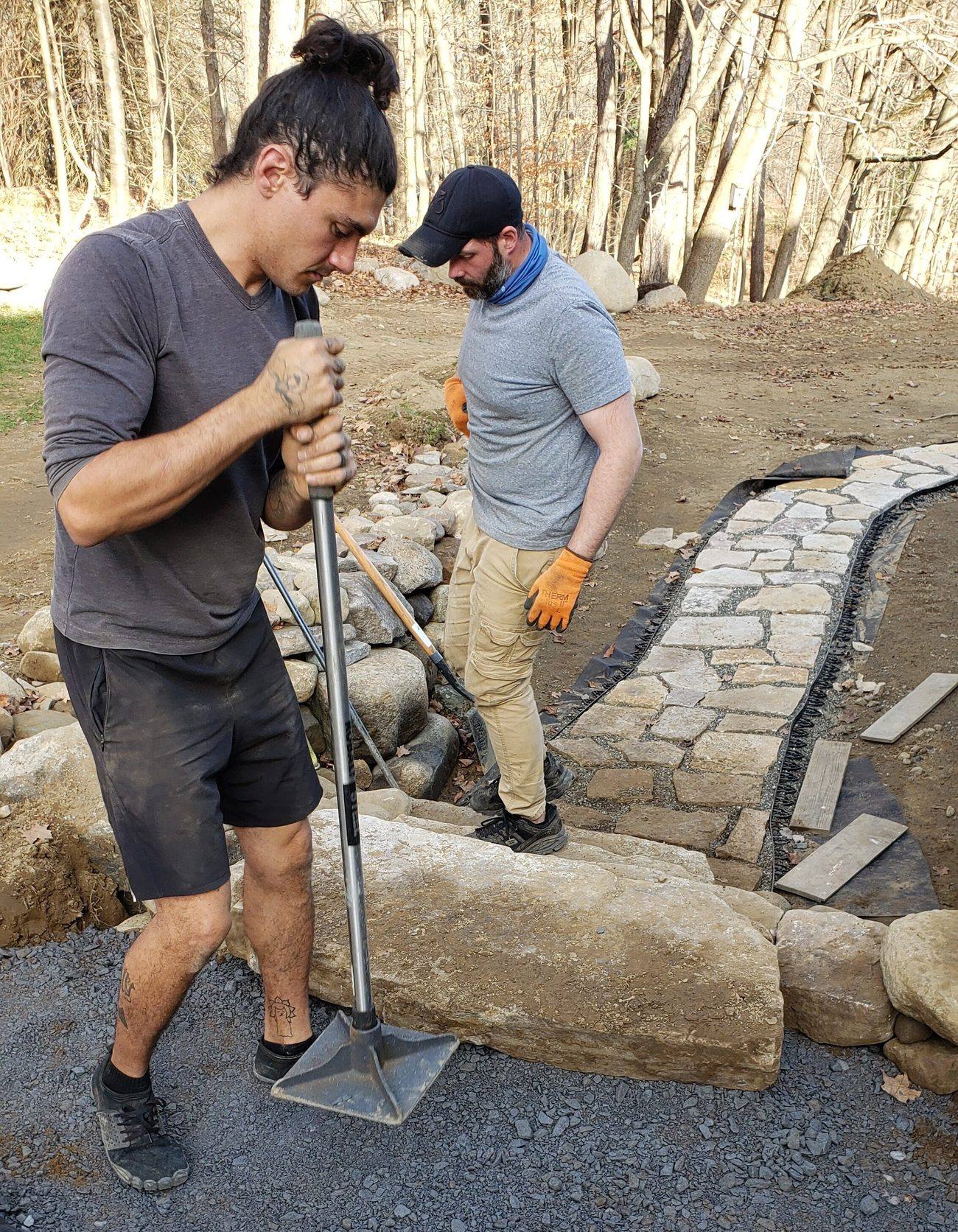 Crew digging and setting stone along a garden edge