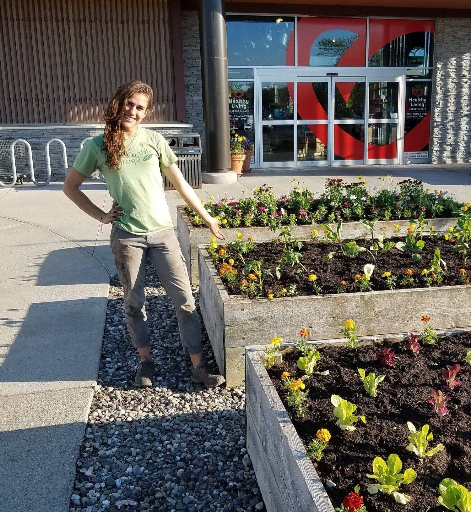 Rachelle Thomas standing beside a newly planted storefront garden bed